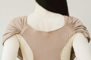 Back view of a woman wearing a beige Konny Baby Carrier FLEX SoftBreeze™, showing the shoulder and back panel